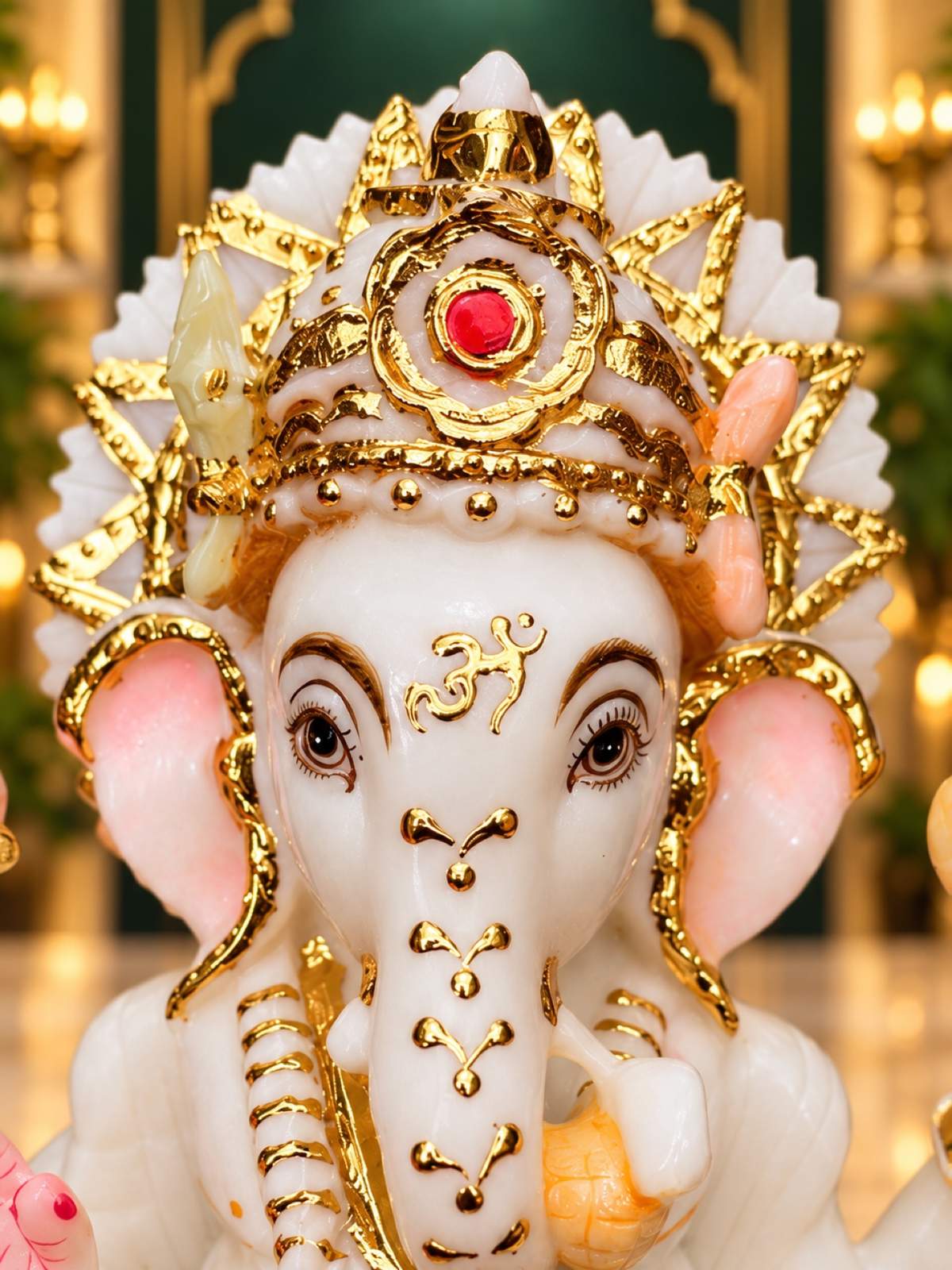 Close-up of Ganesha crown with cut gold detailing and red stone